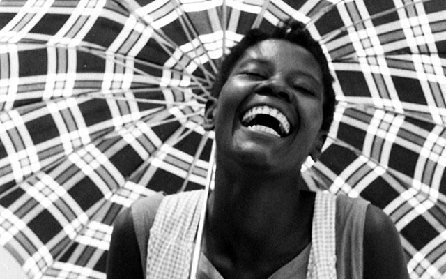 Mujer de Cartagena sonríe mientras se cubre con una sombrilla