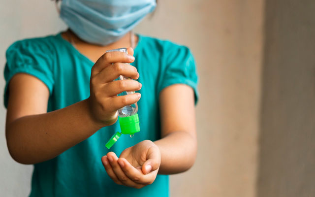 Niña con tapabocas y gel para prevenir el COVID-19