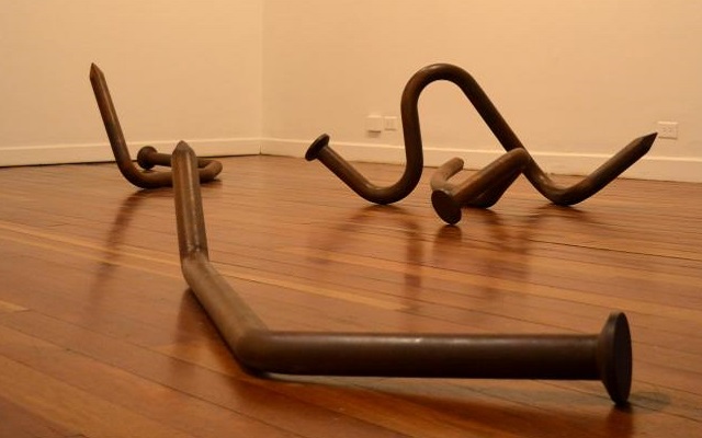 La obra expuesta, revela unos clavos gigantes, enroscados en distintas formas y puestos cuidadosamente sobre el suelo