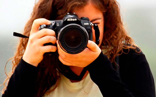 Joven tomando fotografía con cámara Nikon 