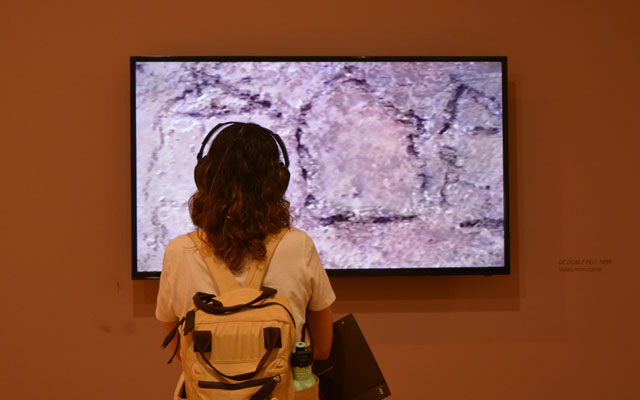 Joven con audífonos observando una obra de Liminal de Clemencia Echeverri