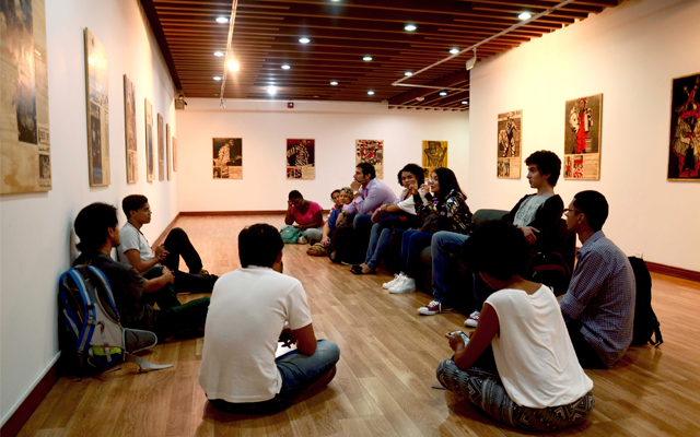 grupo de personas sentadas en el suelo observando exposición