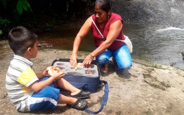 Mamá e hijo, miembros de la comunidad indígena Inkal Awá, explorando la maleta del Museo del Oro
