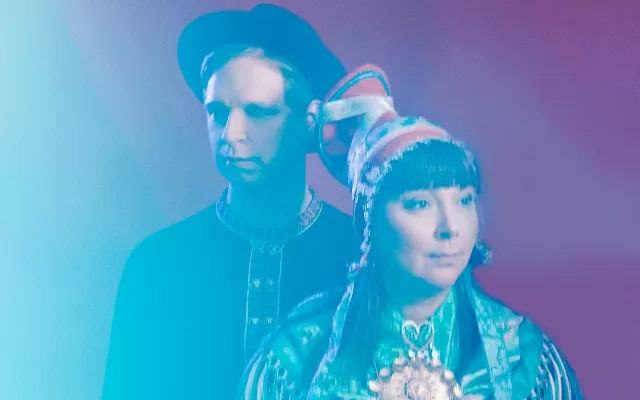 Dos músicos observado diferentes puntos, en un plano medio, con colores difusos