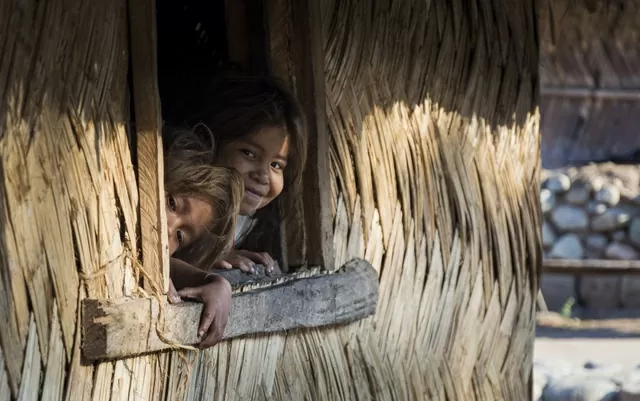 Dos niñas arhuacas asomándose por una ventana 