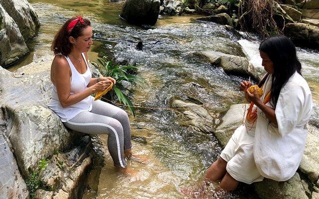 Una mujer wiwa y la artista están tejiendo en un río de la Sierra Nevada de Santa Marta. Artista Victoria Eugenia García 
