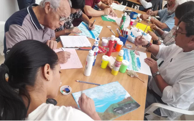 Un grupo de adultos se encuentran en un taller pintando paisajes 
