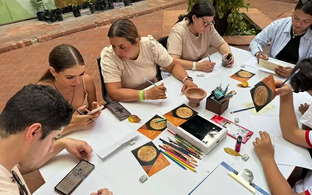 Grupo de personas alrededor de una mesa dibujando una pieza de orfebrería