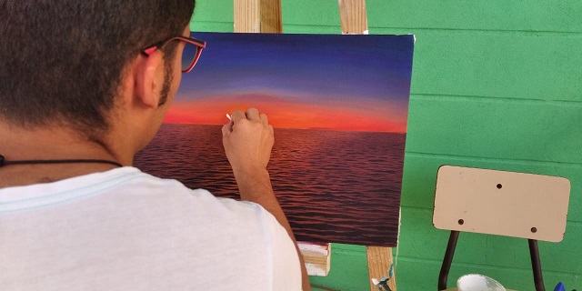 Hombre pintando atardecer realista