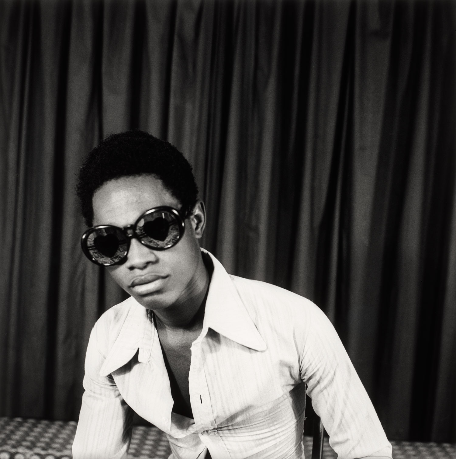 Autorretrato de Samuel Fosso de lentes oscuros y camisa blanca mirando a la cámara