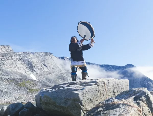Persona tocando tambor encima de rocas