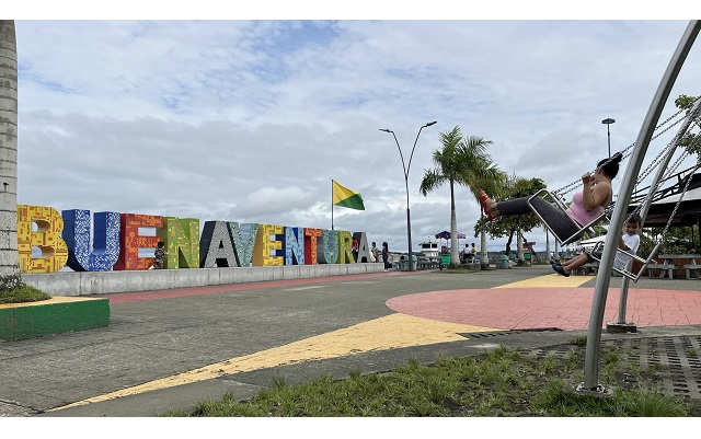 Mujer y niño en columpios frente al ícono de Buenaventura