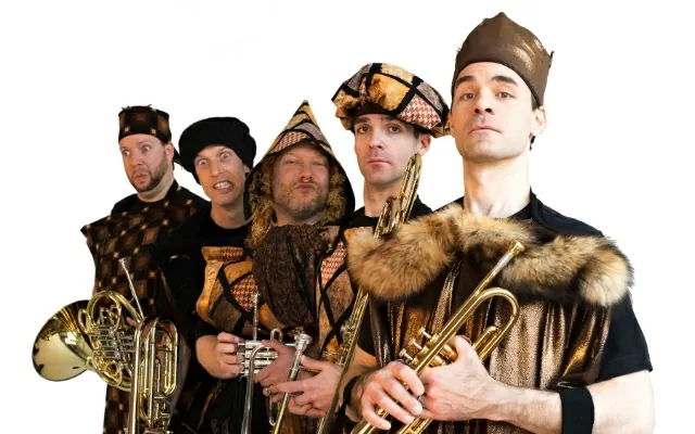 Imagen a color de cinco músicos, usando gorros, posando con sus instrumentos