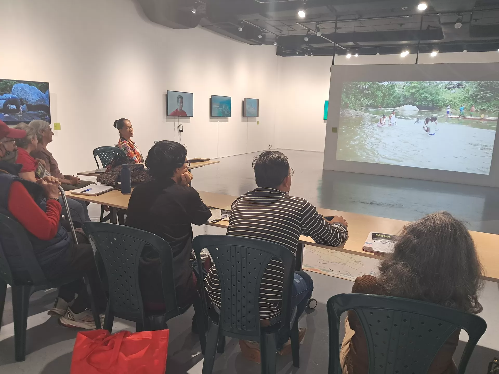 Hombres y mujeres reunidos en torno a una mesa, conversando sobre la exposición de video Déjala Correr que están conociendo