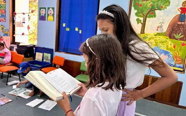 Dos niñas de espalda leyendo un libro 