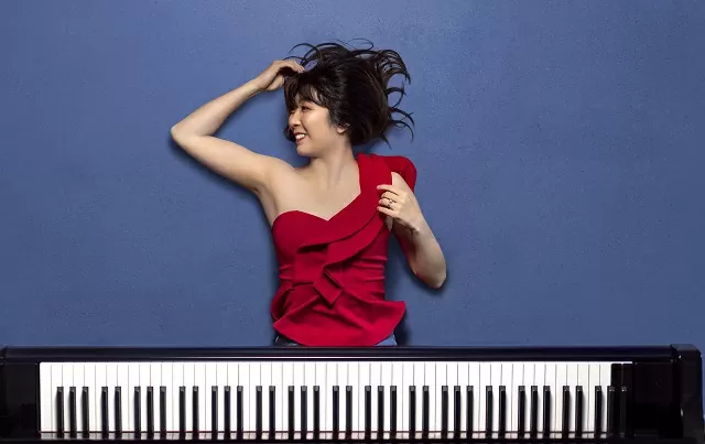 Mujer con vestido rojo debajo de un piano