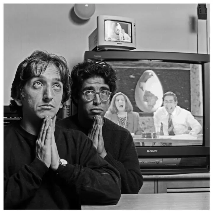 Retrato en blanco y negro de Diego León Hoyos y Jaime Garzón ambos con las manos unidas y detrás de ellos un televisor con el noticiero Quack