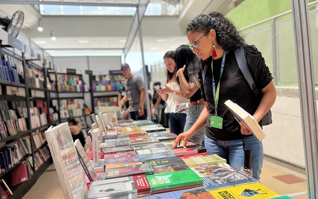Una joven revisa unos libro exhibidos sobre una mesa 