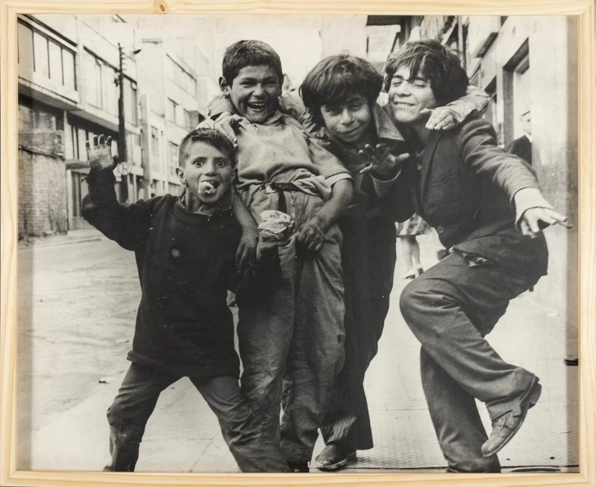 Fotografía en blanco y negro de cinco niños habitantes de calle abrazados y sonriendo a la cámara