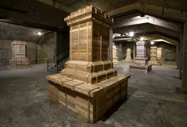 Plano general de la instalación artística Héroes Mil. Se ven varias esculturas en madera, con forma de base de monumentom,