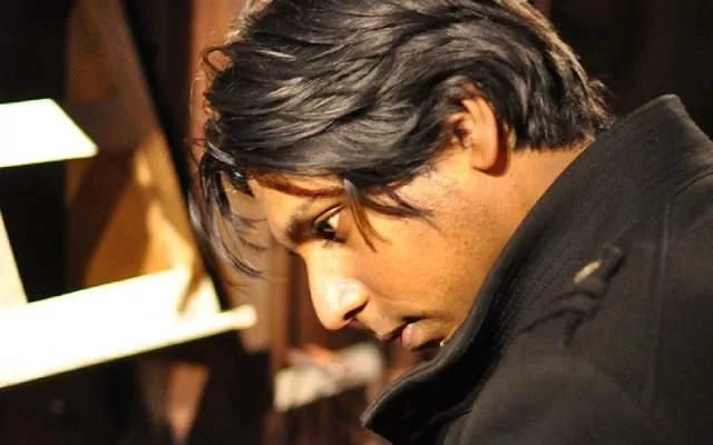 Artista vestido de negro, en plano medio, tocando el órgano café