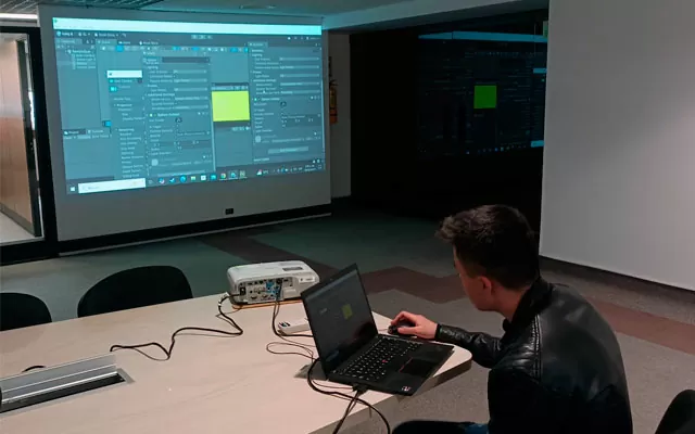 joven trabajando en software de creacion de juegos y proyectando su pantalla