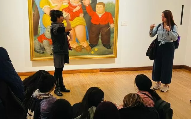 Fotografía donde se ve una mujer hablando con otra en lengua de señas colombiana en una sala del Museo Botero