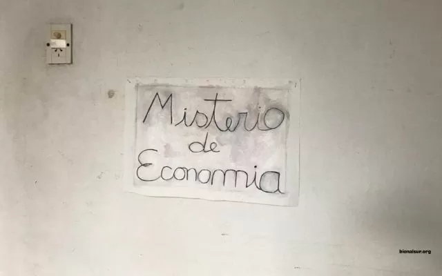 Misterio de Economía. Homenaje a Manuel Peralta Ramos. Laura Ojeda fotografía de un papel con una frase escrita: Misterio de Economía