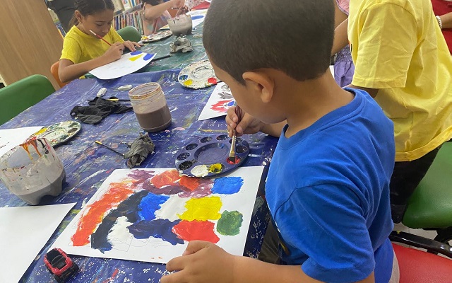 Niño pintando sobre un papel con diferentes colores de pintura 