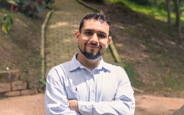 Retrato a color de músico a medio plano, con los brazos cruzados, sonriendo 