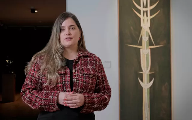 Dariana Rodríguez, hablando en una obra comentada, frente a la obra Tótem de Wifredo Lam 