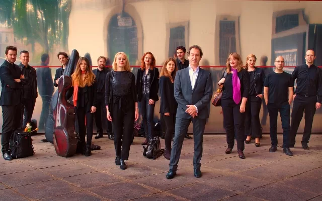 Grupo de mujereres y hombres, en plano completo, al aire libre, vestidos de negro