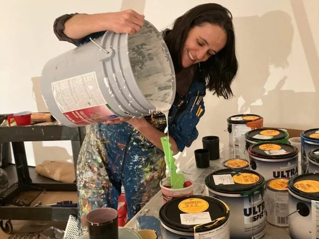 Imagen donde se ve una mujer volteando pintura en unos tarros