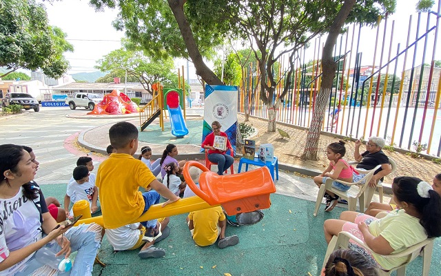 Grupo de niños y niñas en un parque de la ciudad de Santa Marta escuchando atentos una lectura 