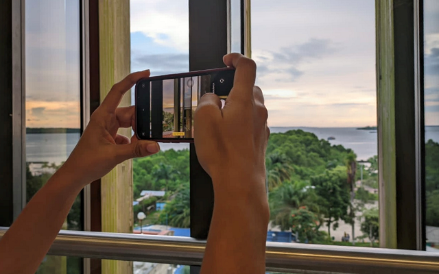 Manos tomando fotografía a atardecer en Buenaventura