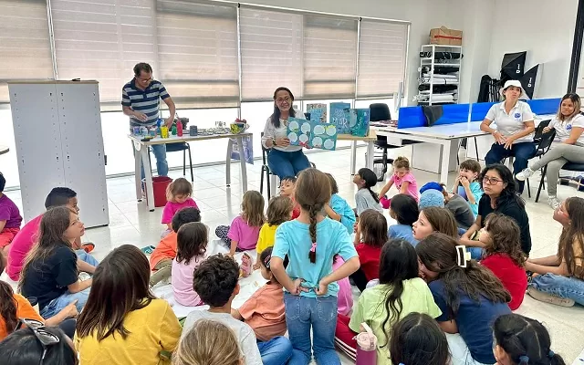 Una señora enseñando un libro a un grupo de niños y niñas