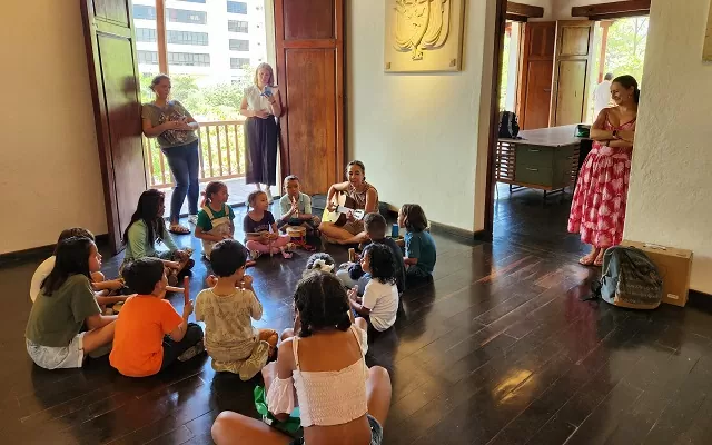 Niños cantando con la tallerista que toca la guitarra 