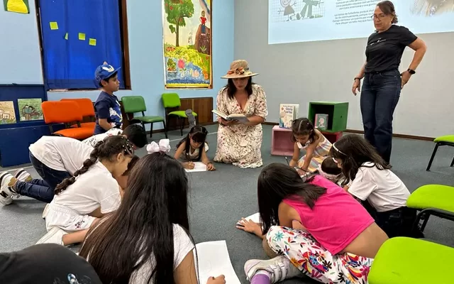 Grupo de niños leyendo, acostados sobre una alfombra 