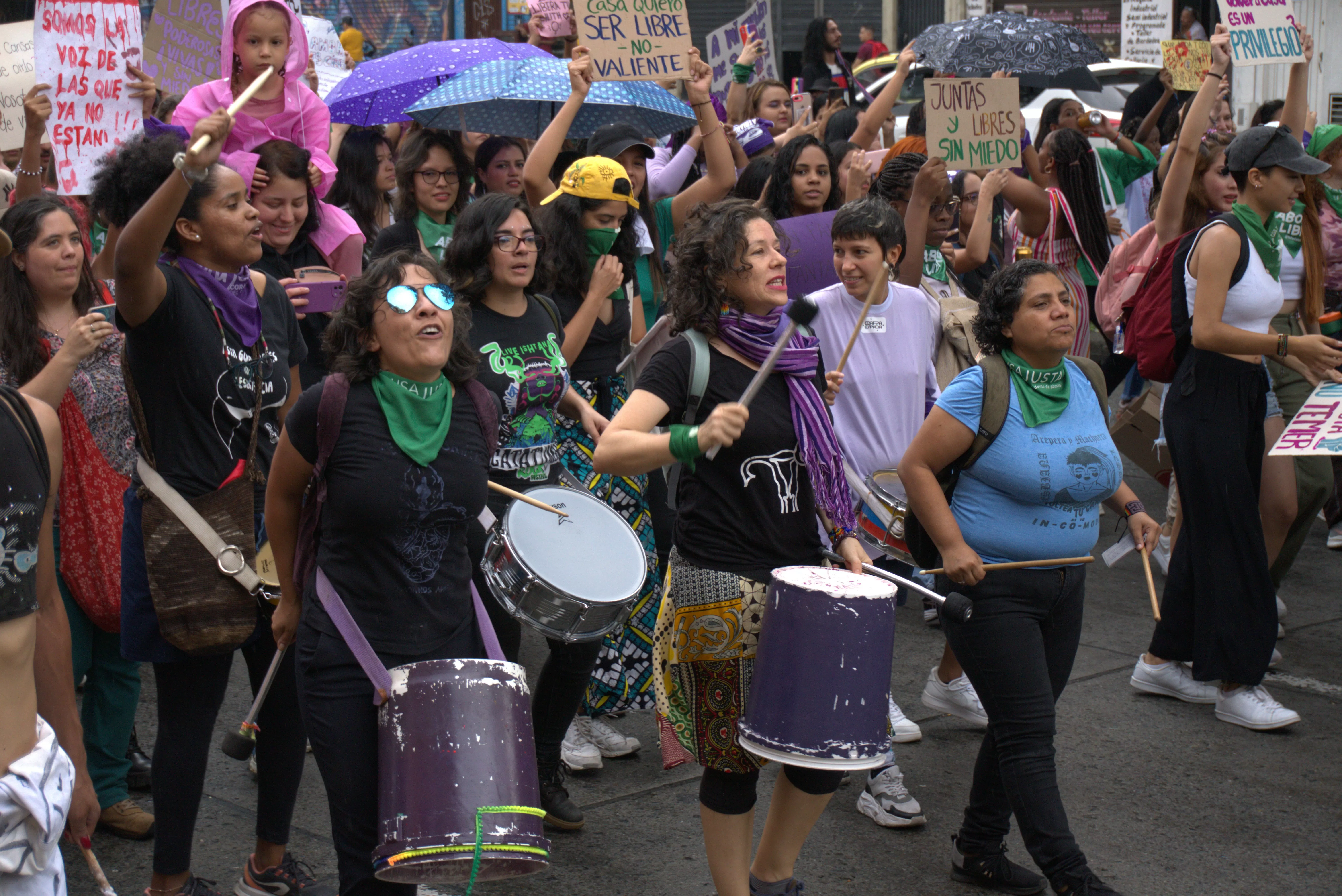 mujeres en una marcha del 8 de marzo tocando tambores y cantando