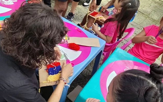 adultos tejiendo con niños utilizando lana de colores