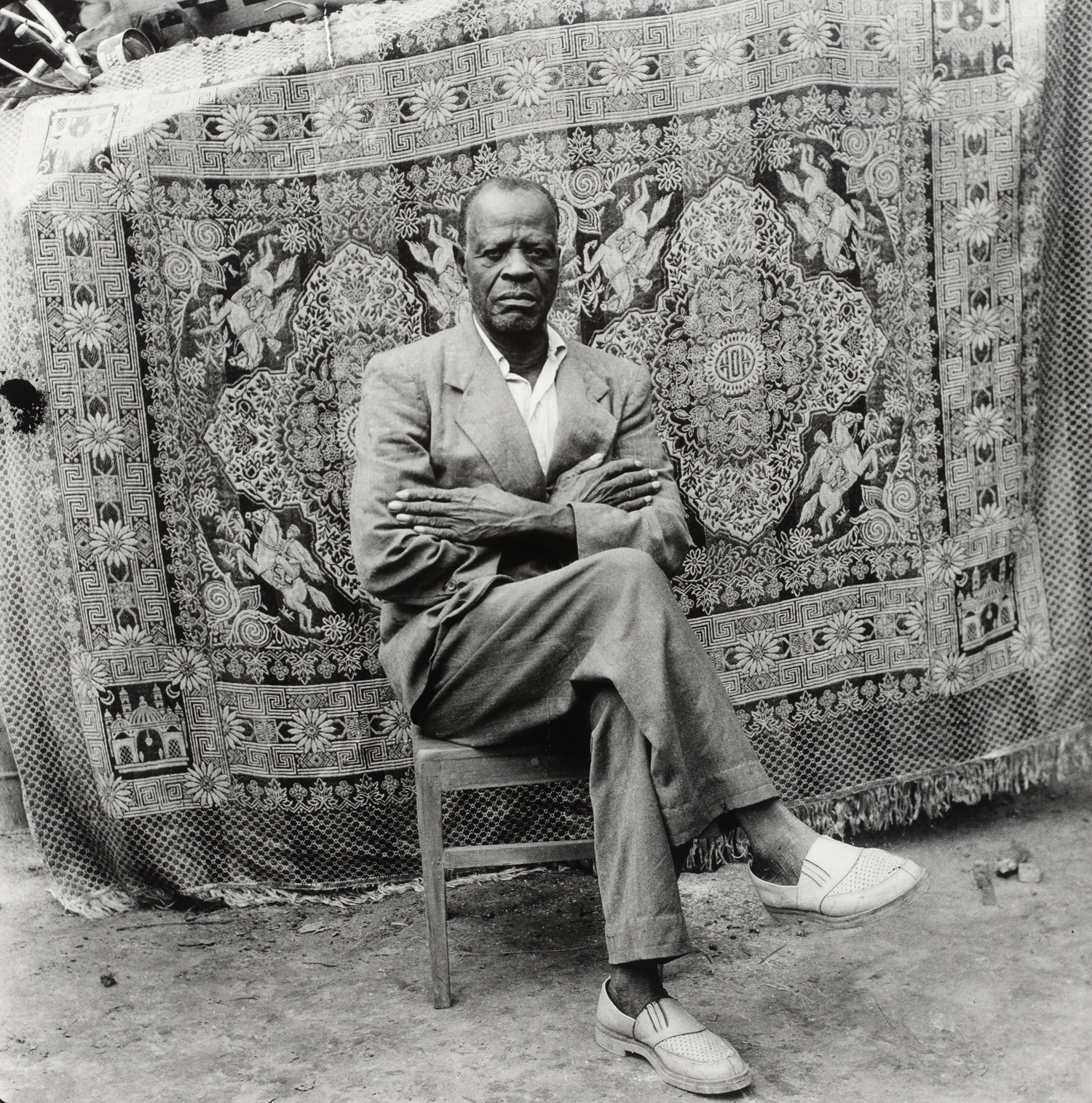 Hombre sentado de brazos cruzados, mirando a la cámara. fotografía en blanco y negro