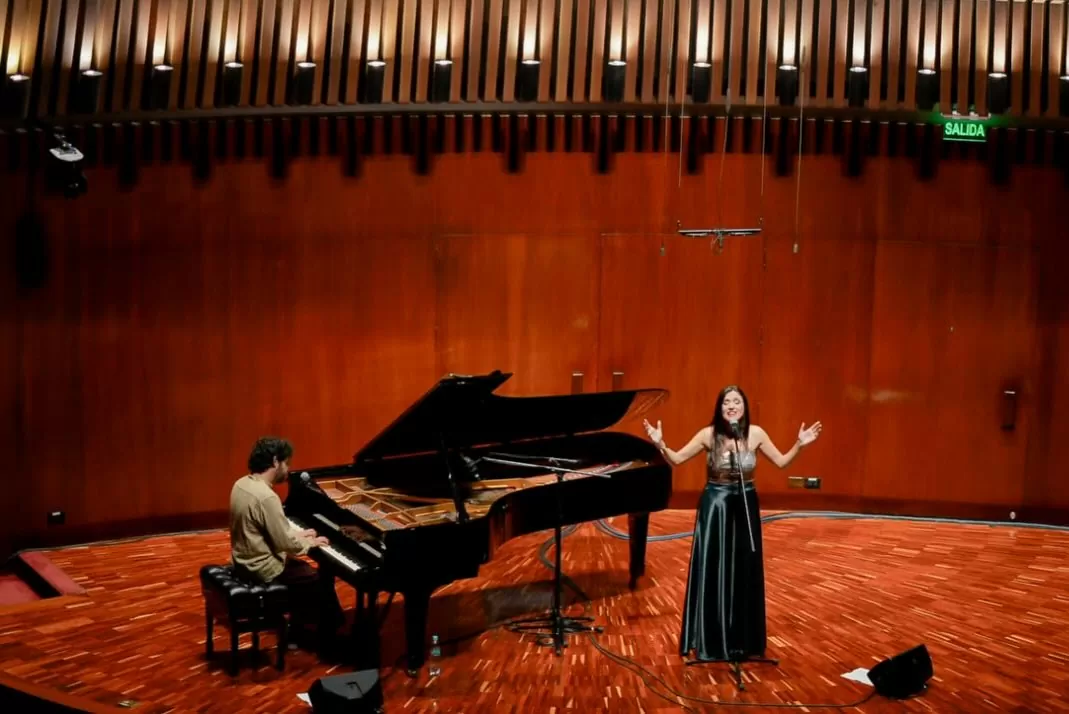 Fotografía de Victoria Sur cantando y Nicolás Ospina tocando el piano