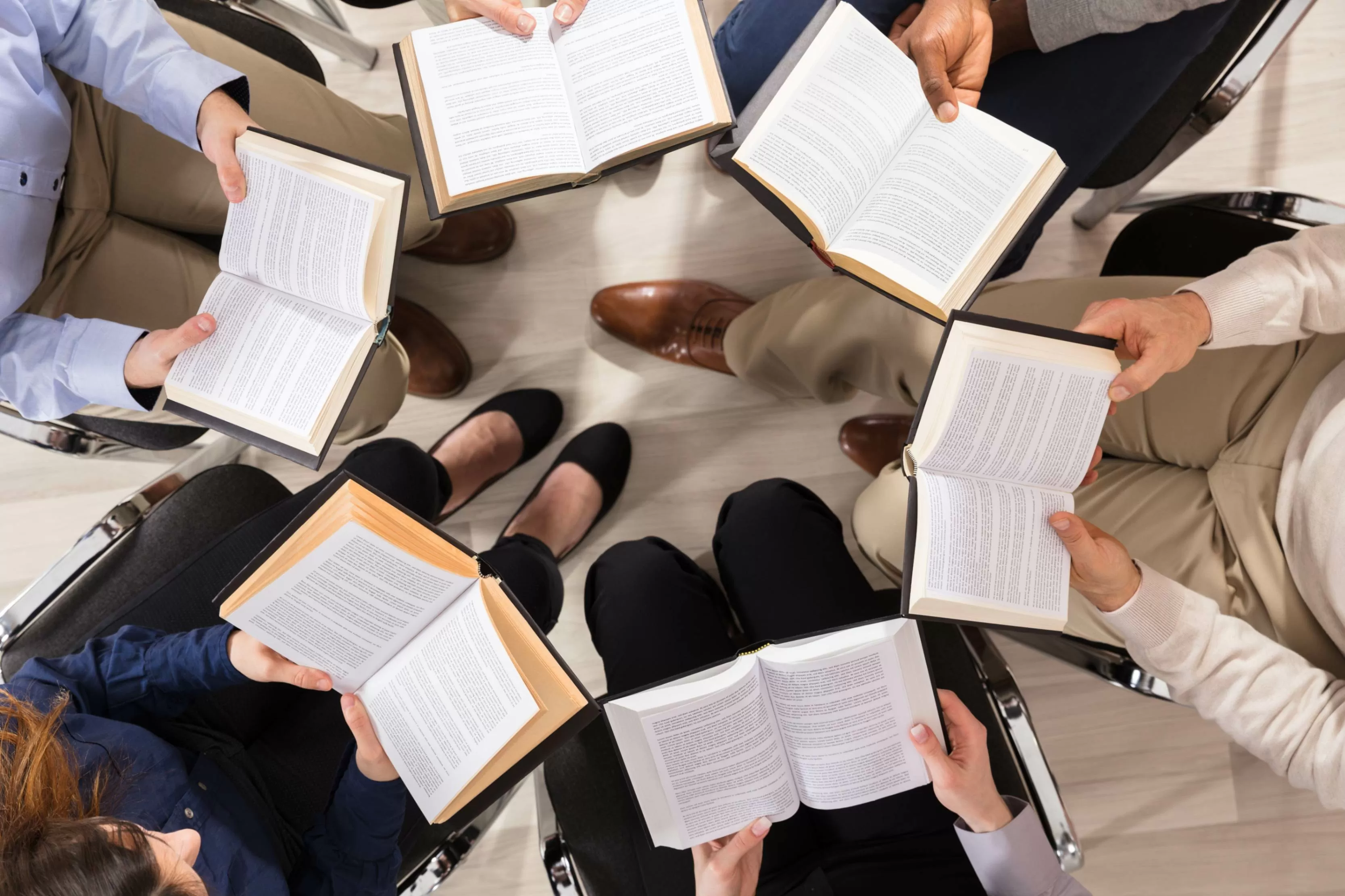 Grupo de personas leyendo con los libros abiertos,  visto desde arriba