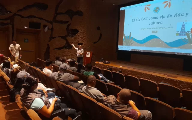 Un grupo de personas en un auditorio escuchan una conferencia sobre el río Cali