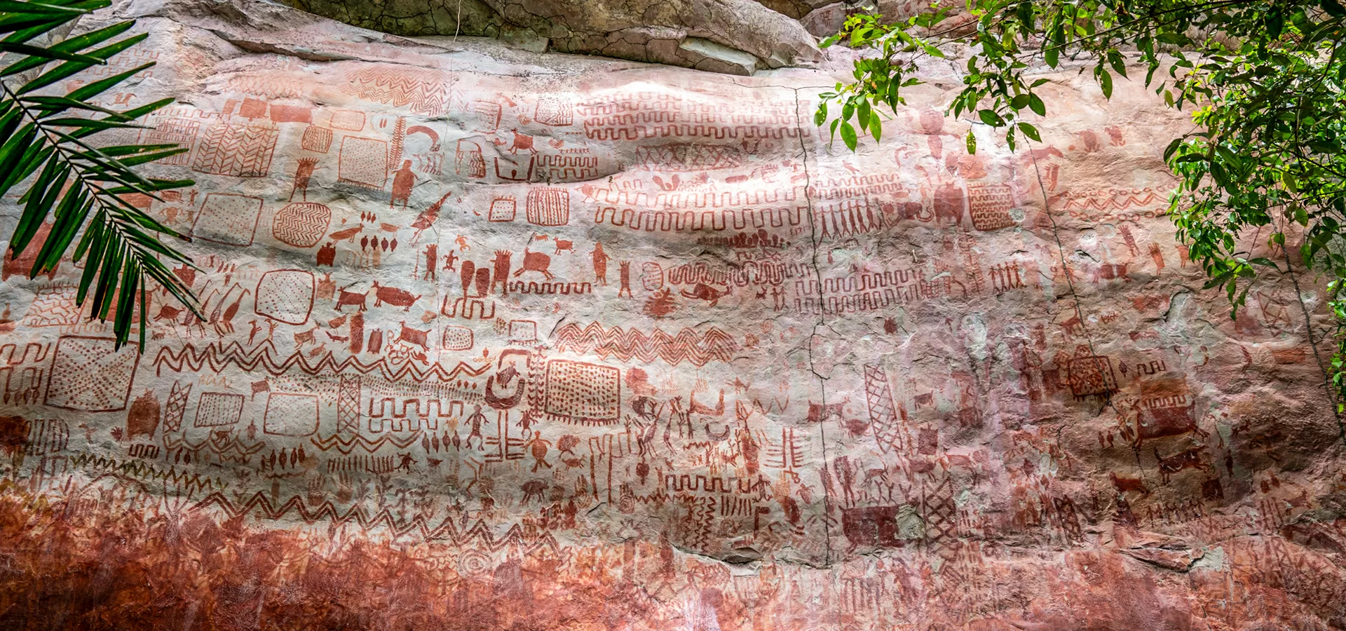 : Esta imagen muestra un gran panel de arte rupestre ubicado en una pared rocosa del Cerro Azul, en el Guaviare, Colombia. 