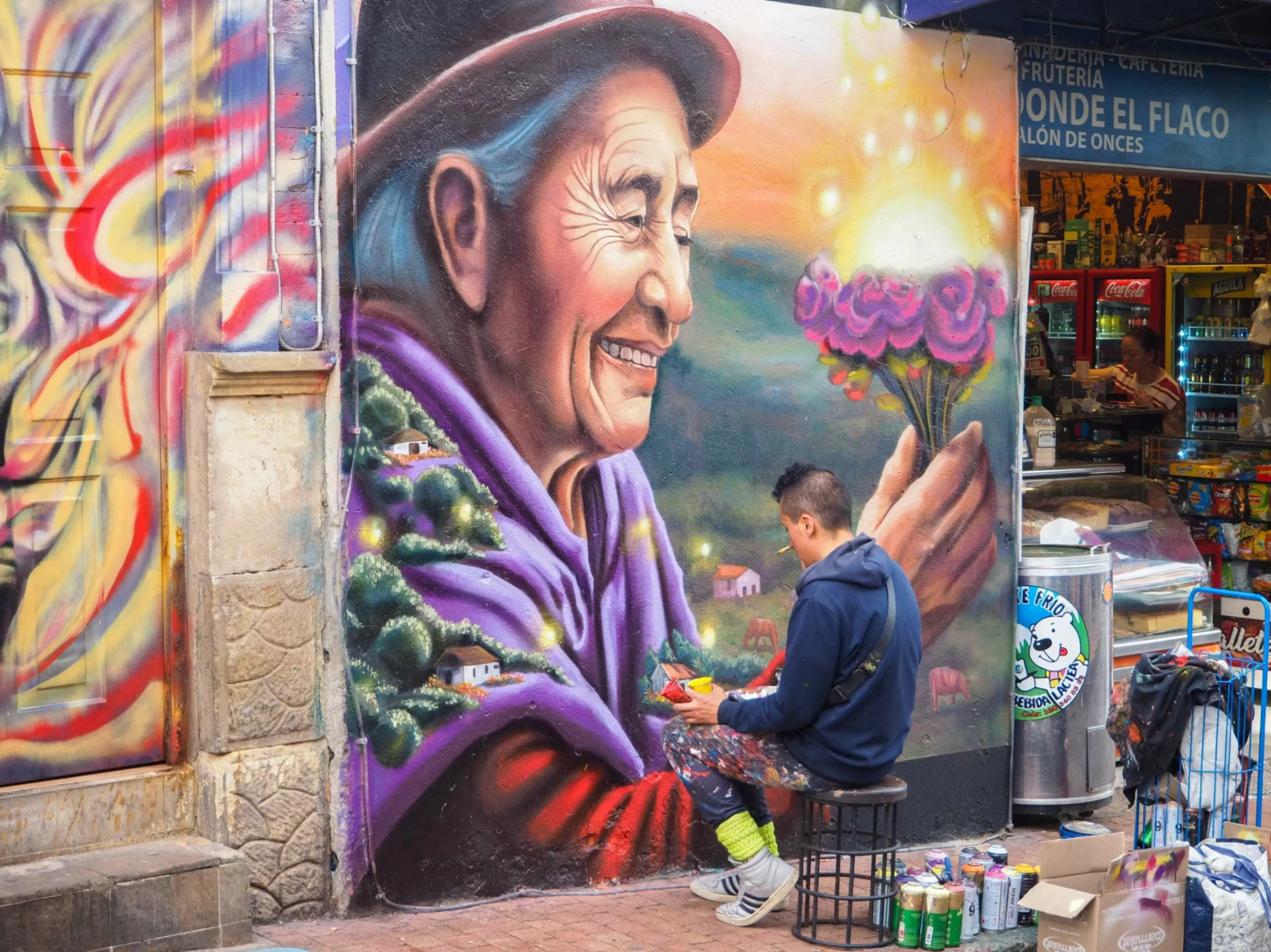 Artista urbano pinta un colorido mural de mujer mayor campesina en Bogotá, Colombia