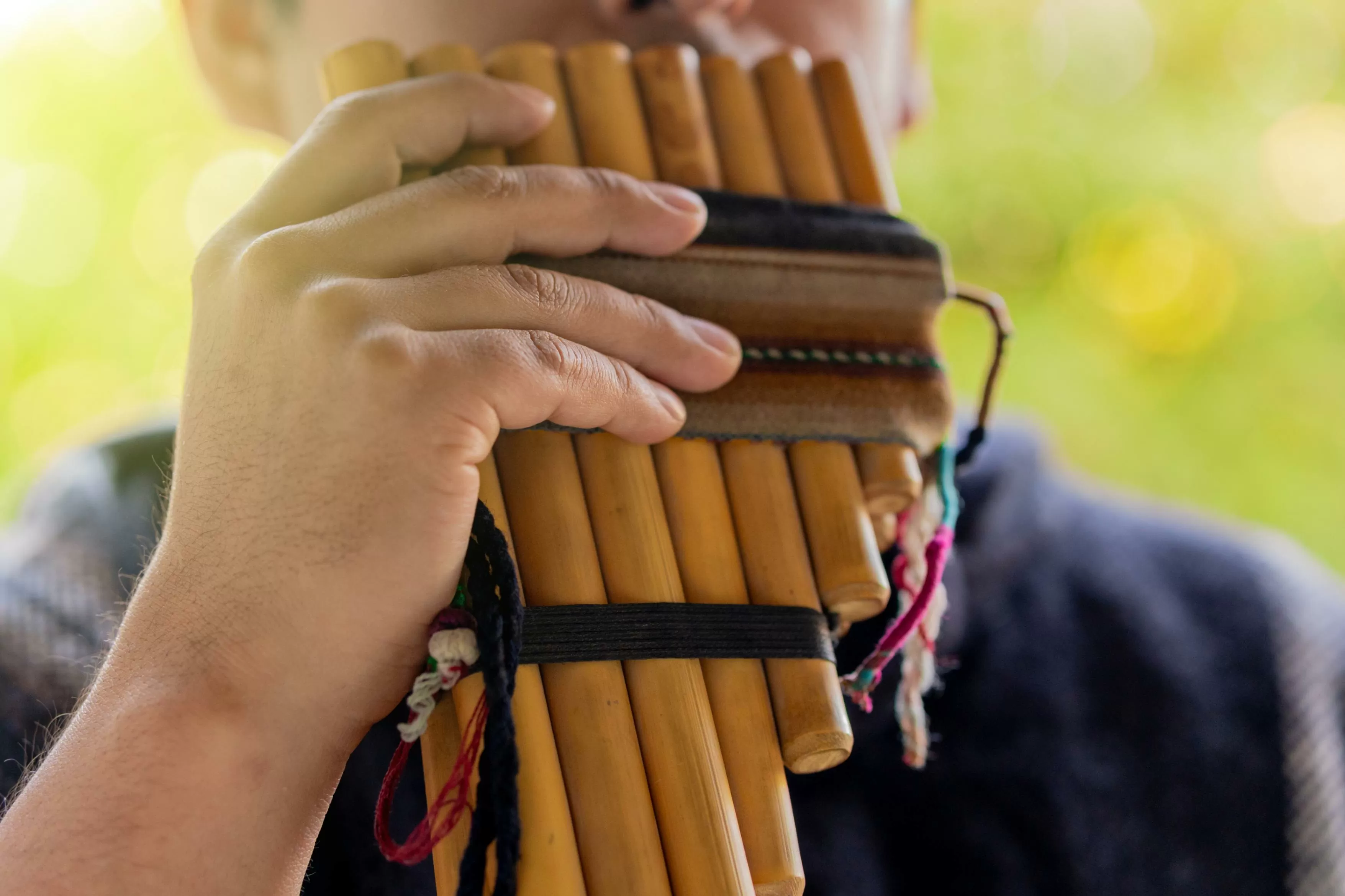 Primer plano de un joven andino tocando zampoña, un instrumento musical tradicional andino.