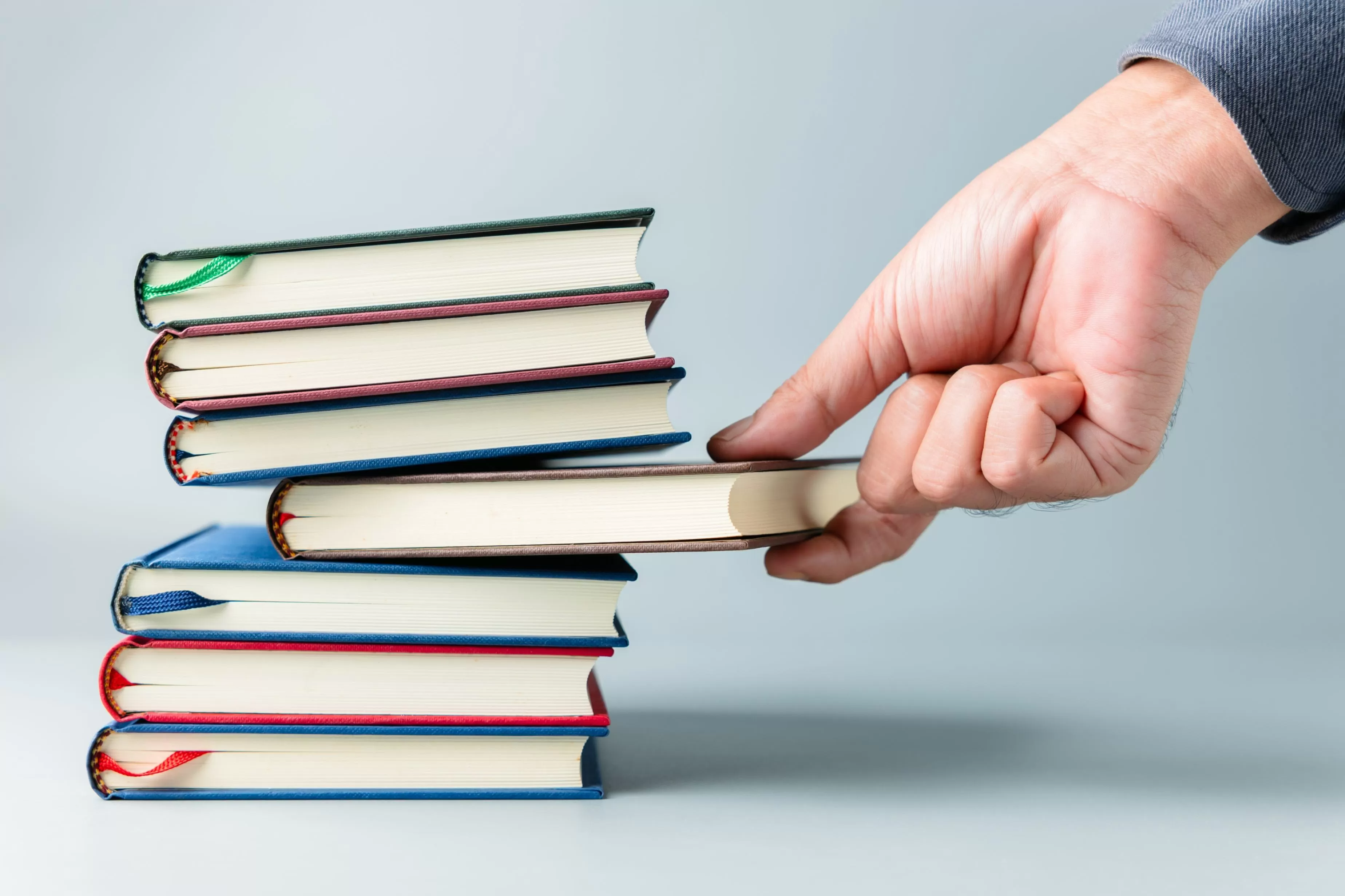 de una pila de libros una mano selecciona uno 