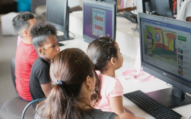 Niñas y sus padres consultando los recursos electrónicos de la Red de Bibliotecas del Banco de la República