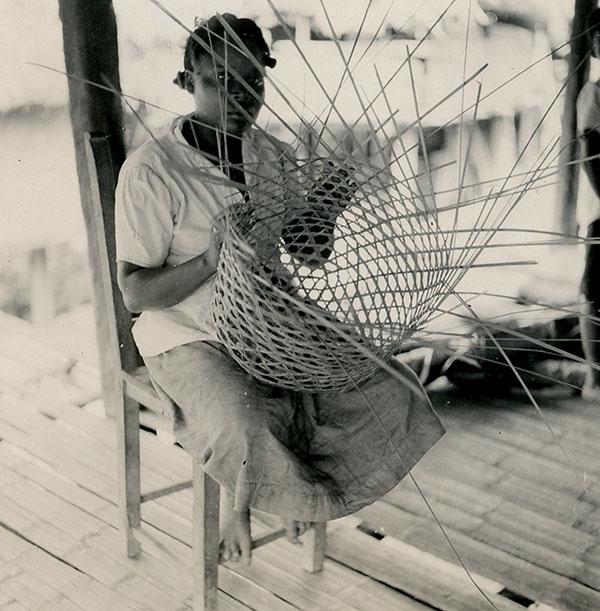 Retrato de mujer afrodescendiente tejiendo un canasto